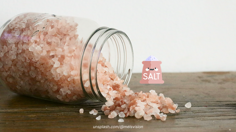 Toples garam himalaya yang terbuka dan garamnya di atas meja